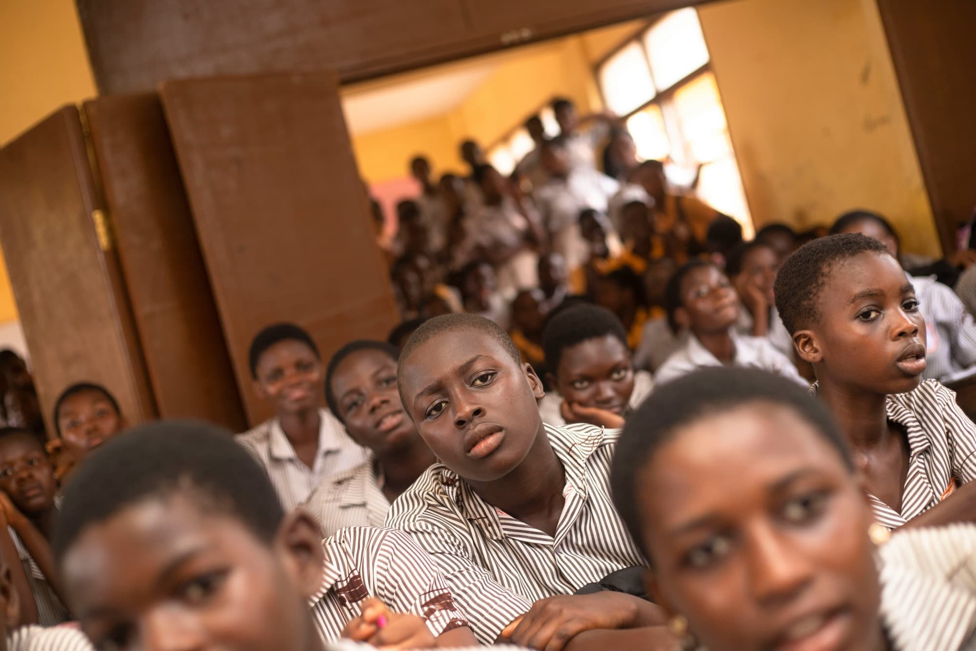 Students in school uniforms listening closely in a classroom in Accra