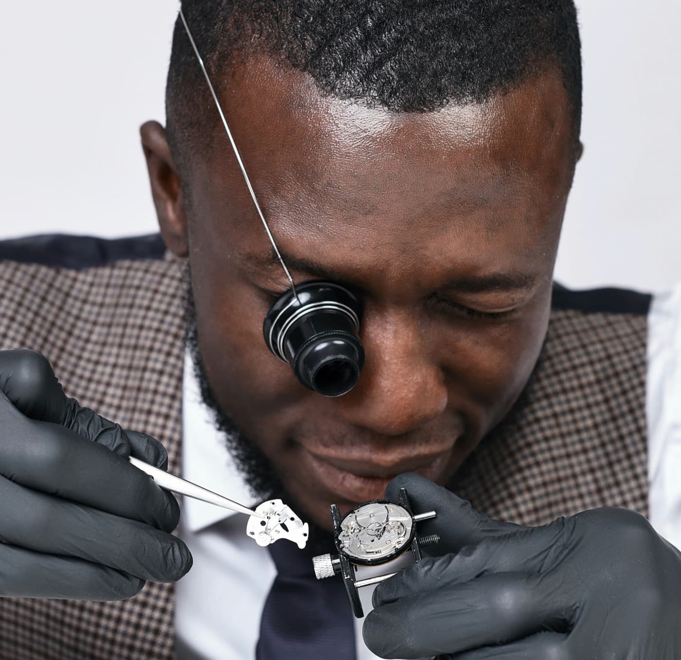 A watchmaker in Accra using an eye loupe to repair a watch movement